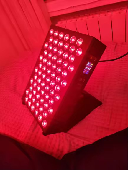 The Tabletop on a bed during an evening session, red light filling the room, on the included floor stand