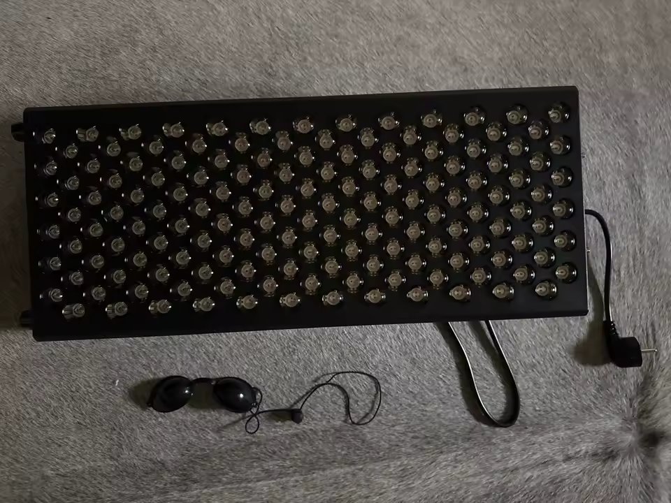 The Tower laid flat on a rug showing the full 5 by 30 array of 150 LEDs, with included protective eyewear and power cord
