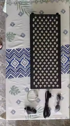 The Tower laid flat showing the full LED grid, with power cable, US plug adapter, and protective eyewear accessories on a patterned fabric